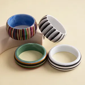 Close-up detail of retro resin striped bangles with vibrant multi-color and monochrome patterns.