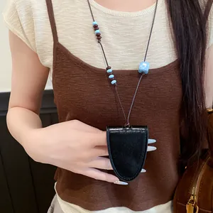 Collier pendentif minimaliste en cuir noir et porte-clés présenté en gros plan sur modèle