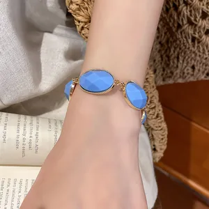 Detail view of a vintage blue oval resin bracelet with gold metal trim on a woman wrist.