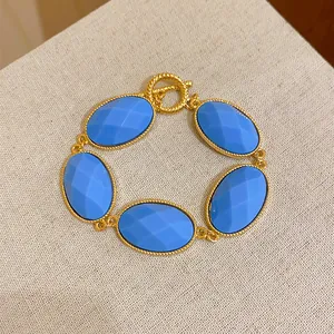 Detail view of gold-tone bracelet with faceted blue oval resin stones in vintage style.