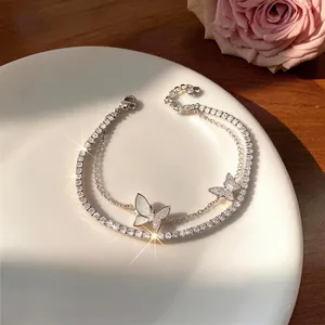 Elegant double-layer silver bracelet featuring zircon-encrusted butterfly charms on a white plate