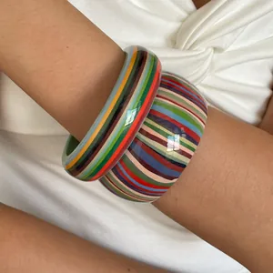 Close-up view of retro multi-color striped resin geometric bracelets on a model wrist