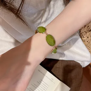Detailed close-up of a retro green resin oval bracelet on a female model's wrist