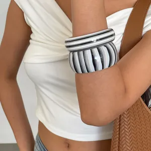 Detailed view of retro resin striped bangles in black and white worn by a model