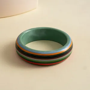 Macro detail of a vintage resin bangle with colorful horizontal stripes on light background