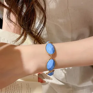 Close-up of blue resin oval bracelet with gold-tone metal edging on woman's wrist