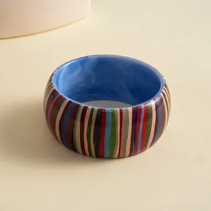 Close-up of vintage resin bangle with colorful vertical stripes and blue interior