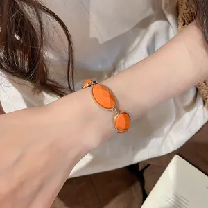 Close-up of a vintage orange resin oval bracelet with gold-plated trim on a wrist