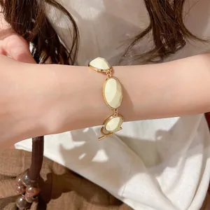 Close-up view of retro gold-tone bracelet with oval cream faceted resin on wrist