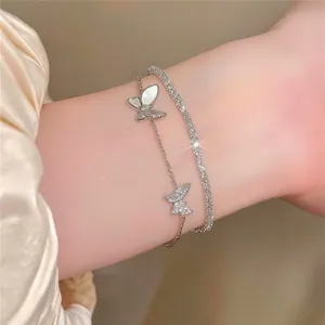 Detailopname van een sprankelende dubbellaagse armband met vlinderbedels van zirkoon.