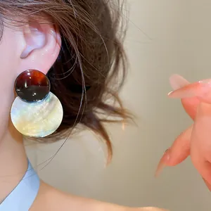 Nahaufnahme eleganter Muschel-Ohrhänger mit Acryl-Verlauf, getragen von einem Modell