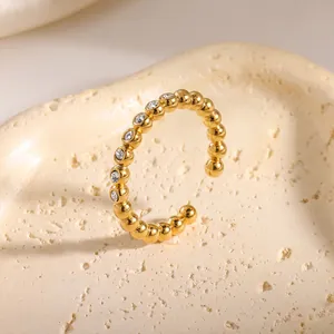 Detailweergave van een vergulde roestvrijstalen ring met kraalstructuur en zirkoon.