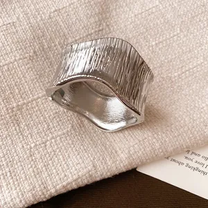 Close-up of minimalist silver wrinkled metal wide ring with textured organic finish