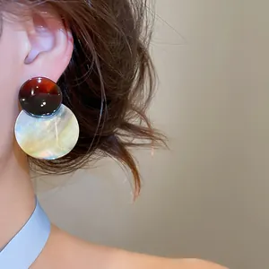 Nahaufnahme von eleganten Schildpatt- und Perlmuttscheiben-Ohrringen an einem Modell