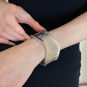 Detailed view of a wide silver metal cuff bracelet with a stylish textured wrinkle design