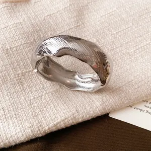 Close-up of a silver-toned crinkled metallic cuff bangle on a textured linen surface.