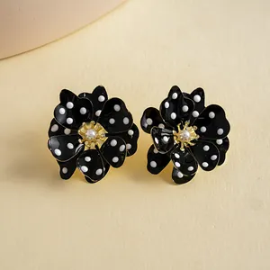 Gros plan détaillé de boucles d'oreilles fleurs noires à pois blancs avec perle centrale