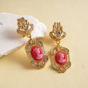 Close-up detail of vintage European palace style cameo earrings with red resin portraits.