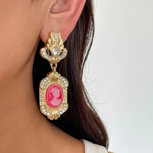 Detailed view of a vintage palace style earring with rhinestone and red cameo portrait