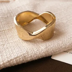 Detailed close-up of a gold wavy metal open bangle with irregular folded texture