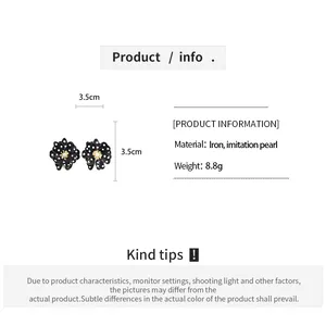 Détail boucles d'oreilles fleurs à pois noirs de 3,5 cm avec centre en perle.