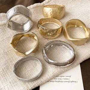 Close-up of assorted matte and textured metal bangle bracelets in gold and silver finish