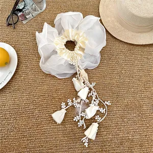 Vue détaillée d'un chouchou en organza blanc avec d'élégants glands de fleurs en dentelle