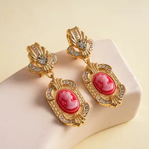 Detail view of vintage palace style earrings with a decorative red cameo and crystals