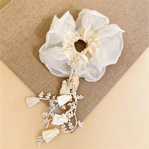 Détail de la dentelle florale et des glands délicats du chouchou en tissu blanc