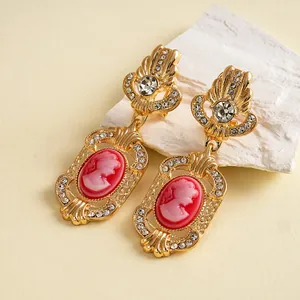 Close-up of vintage palace style gold earrings with pink cameo and rhinestones.