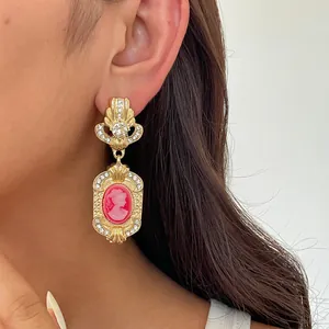 Macro detail of vintage court style gold earring with pink cameo and rhinestones