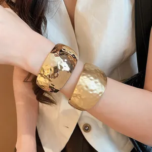 Close-up detail of stylish gold hammered cuff bracelets in polished and matte finishes