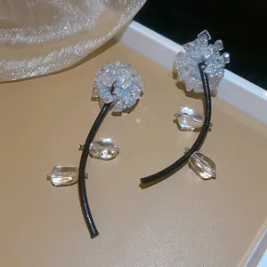 Vue détaillée de boucles d'oreilles fleurs au design unique avec tiges noires et cristaux.