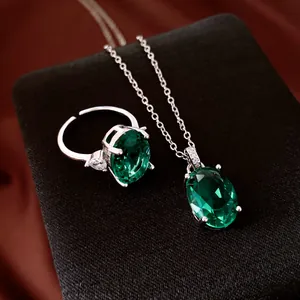 Detailansicht eines silbernen Halsketten- und ovalen grünen Zirkon-Ring-Sets auf Schmuckschatulle