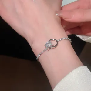 Gros plan d'un bracelet minimaliste à anneaux entrelacés avec zircons sur le poignet.