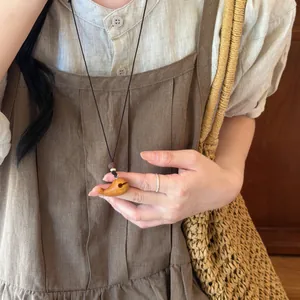Vue détaillée en gros plan d'un collier pendentif baleine en bois artisanal sur cordon
