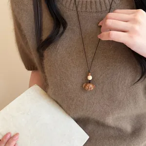 Gros plan d'un collier avec pendentif éléphant en bois fait main sur un pull marron doux