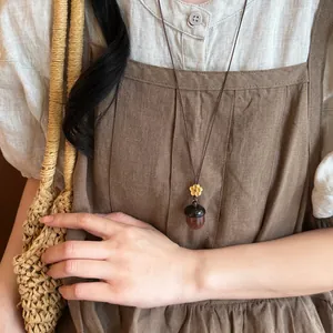 Collier gland en bois fait main avec breloque fleur porté sur un tablier en lin chic