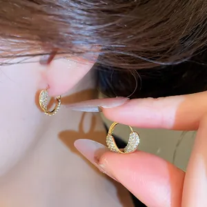 Vue rapprochée d'élégantes boucles d'oreilles créoles dorées avec zircons brillants.