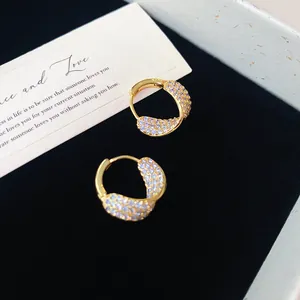 Détail des boucles d'oreilles créoles dorées de style français avec zircons
