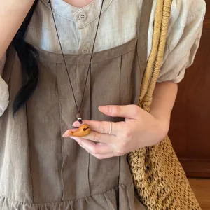 Détail du collier avec pendentif éléphant en bois artisanal sur une robe en lin