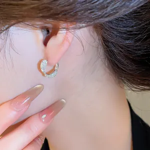 Détail en gros plan d'une boucle d'oreille incurvée en zircone sur l'oreille