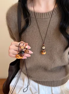 Détail d'un collier avec pendentif en bois fait main avec un éléphant sur un mannequin.