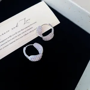 Gros plan de boucles d'oreilles créoles incurvées avec oxydes de zirconium brillants