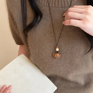 Gros plan détaillé d'un collier pendentif éléphant en bois fait main sur un pull