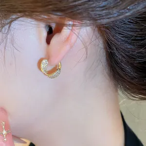 Gros plan de boucles d'oreilles créoles dorées avec des zircons pavés étincelants