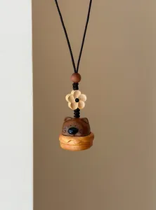 Détail d'un pendentif en bois fait main en forme d'ours avec breloque fleurie