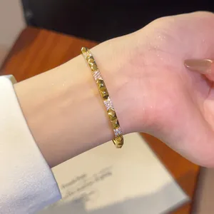 Detailopname van 18K vergulde armband met studs en sprankelende zirkonia