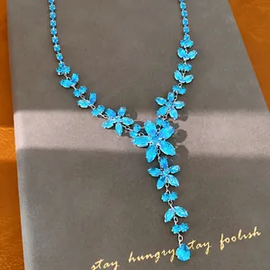 Nahaufnahme einer blauen Zirkonia-Blumenhalskette mit Tropfenanhänger auf Display
