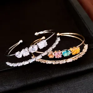 Dettaglio ravvicinato di bracciali rigidi placcati oro 18k con zirconi luccicanti